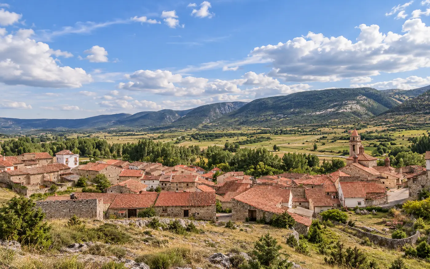 Vista de Fortanete (Teruel) con sus tejados de teja, la torre de la iglesia y el valle con montañas al fondo
